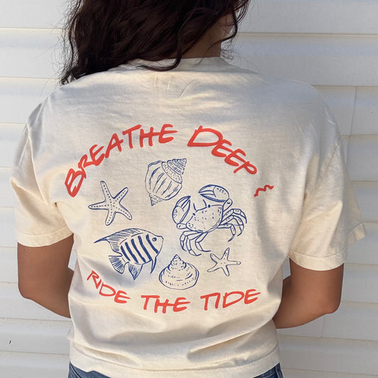 Breathe Deep Ride the Tide graphic t-shirt with ocean-themed seashell and fish design – mental health inspired beachwear