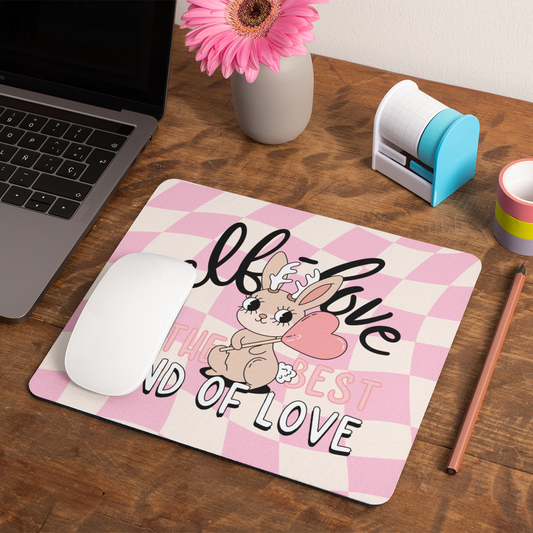 Desk setup with a laptop, mouse, and decorative mouse pad featuring a bunny design.